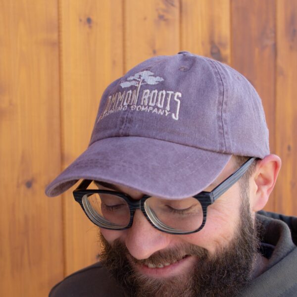 Dusty purple cap with Common Roots embroidered across front in white