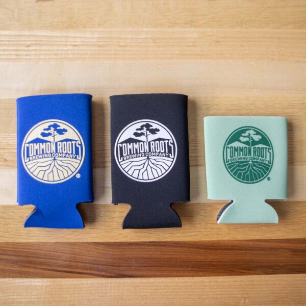 A large royal blue koozie, a large black koozie and a smaller sage green koozie.