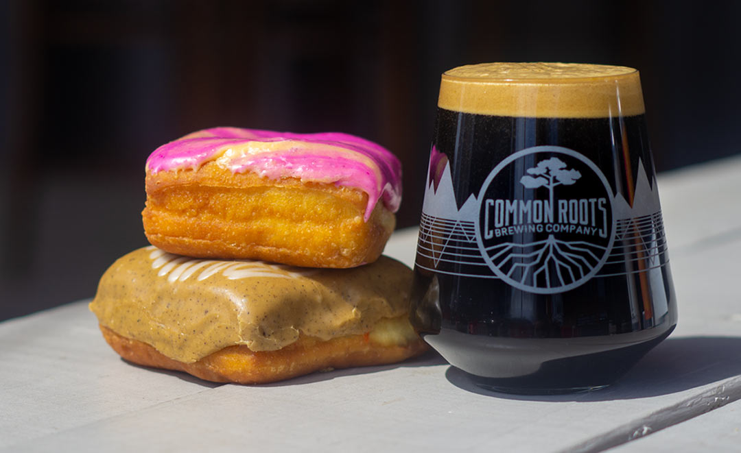 Two colorful doughnuts next to a glass of dark beer