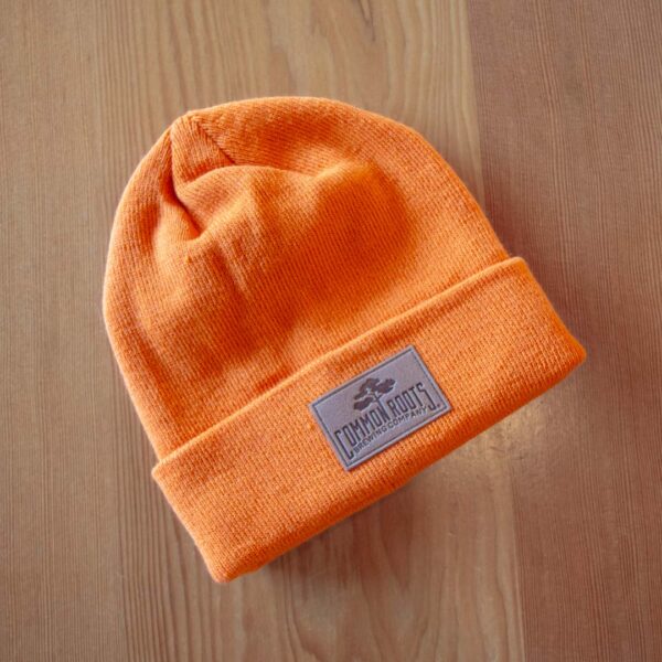 Bright orange beanie with leather logo patch on it