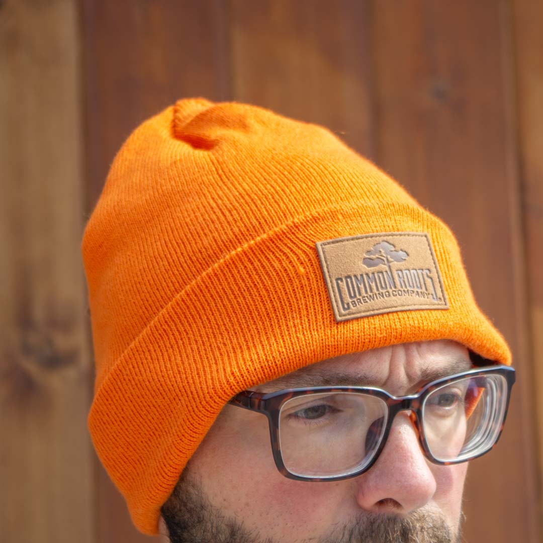 Man wearing bright orange beanie with leather patch on it