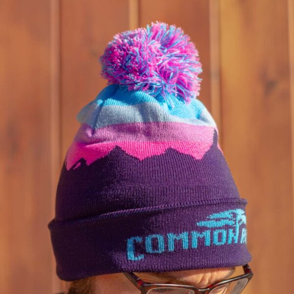 Purple, pink and teal beanie with mountain theme and pom pom.