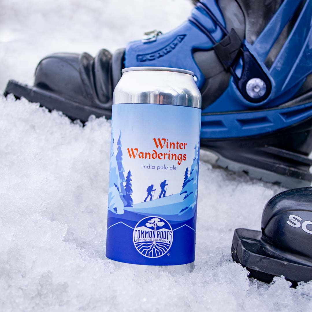 Can of Winter Wanderings in the snow next to ski boots