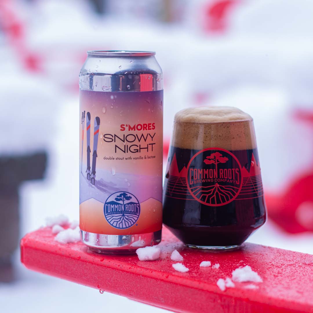 Snowy Night S'mores Can in the snow with a glass of dark beer