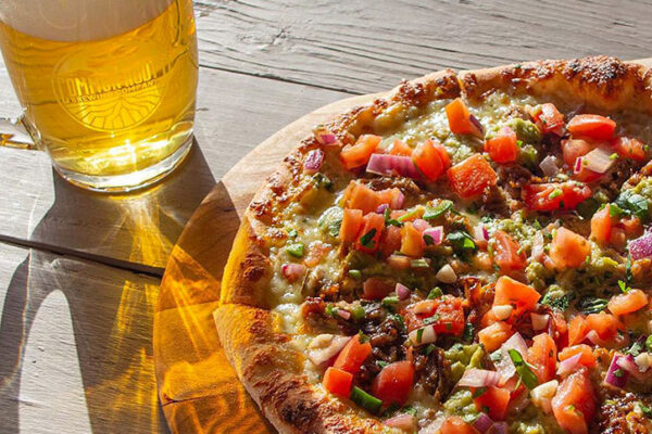 A mixed topping pizza next to a mug of beer