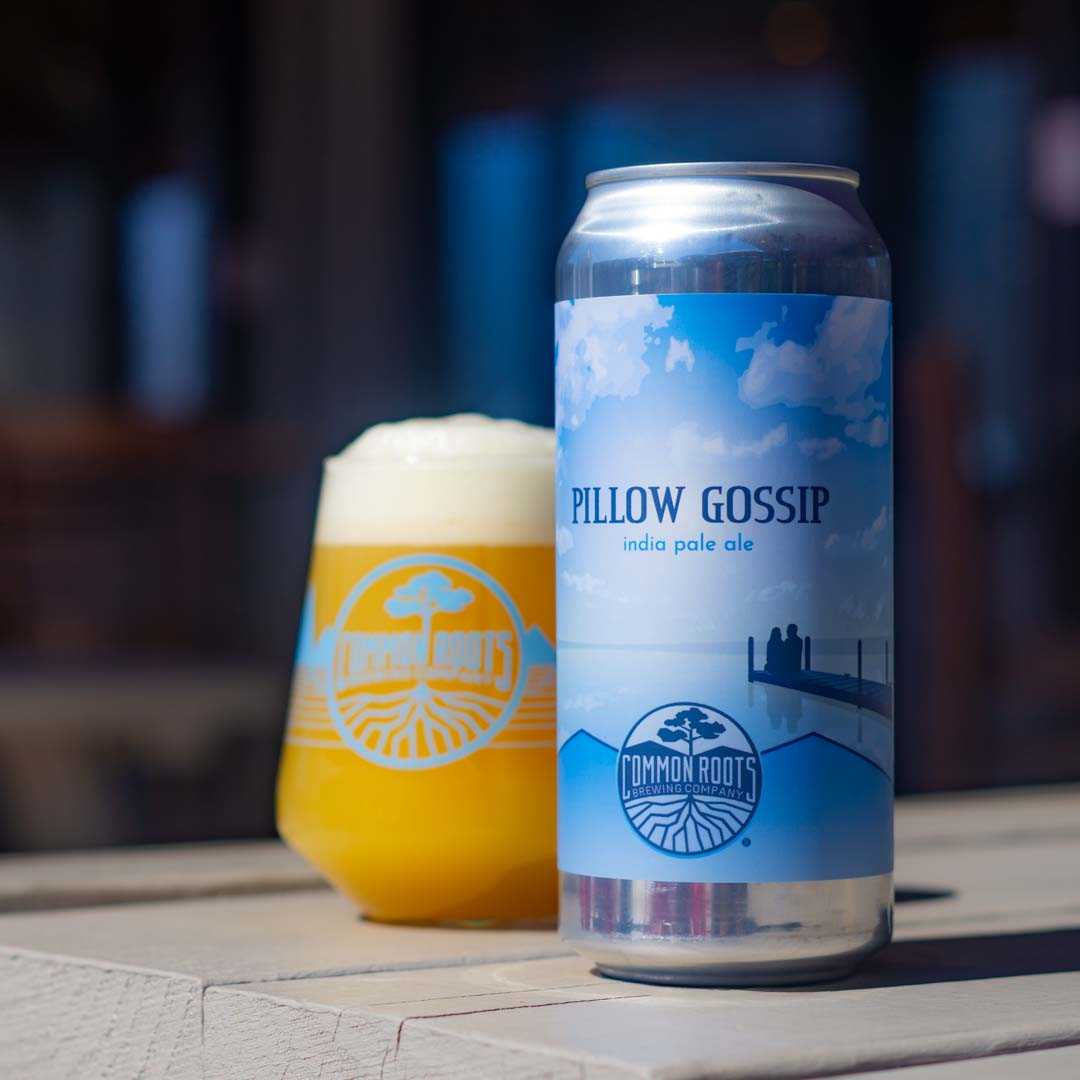 Pillow Gossip can next to a glass of hazy beer