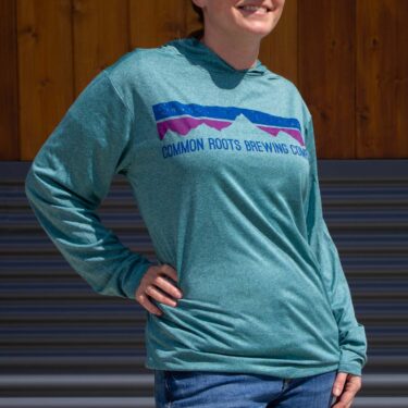 Woman wearing an aqua hoodie with blue and purple mountain graphic on front.