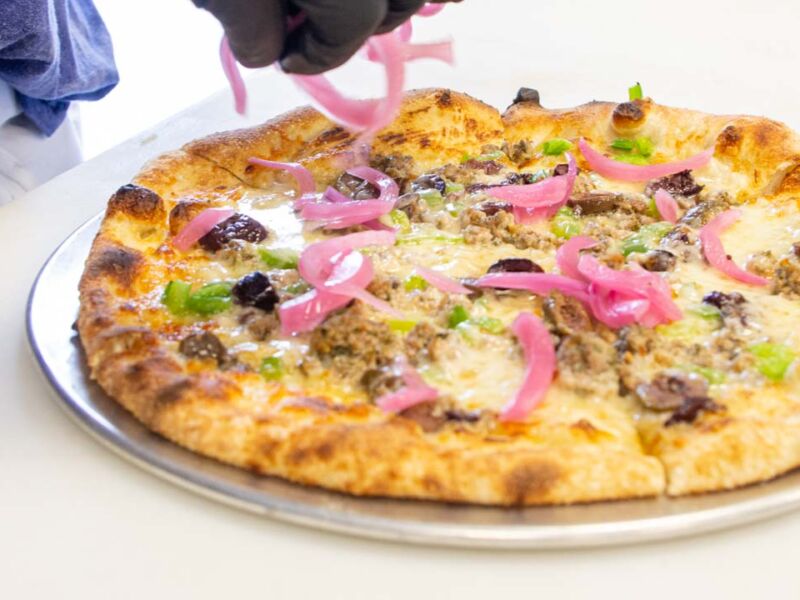 Chef adding toppings to a pizza