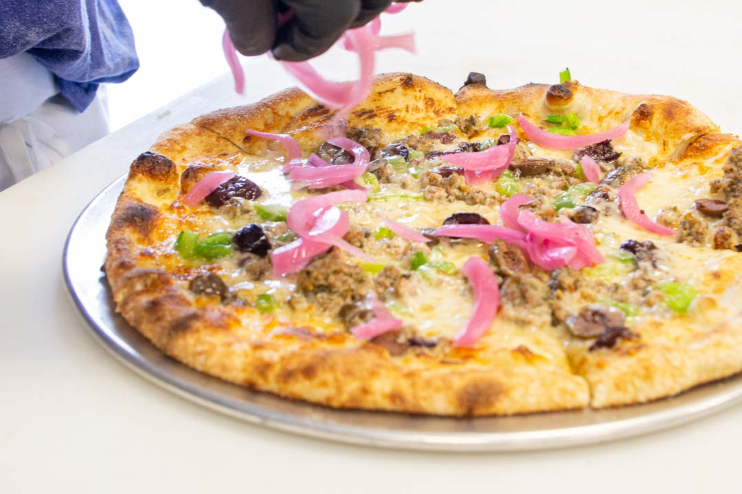 Chef adding toppings to a pizza