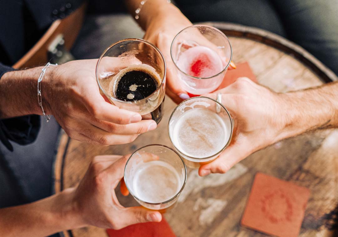 Four people raising glasses of beer