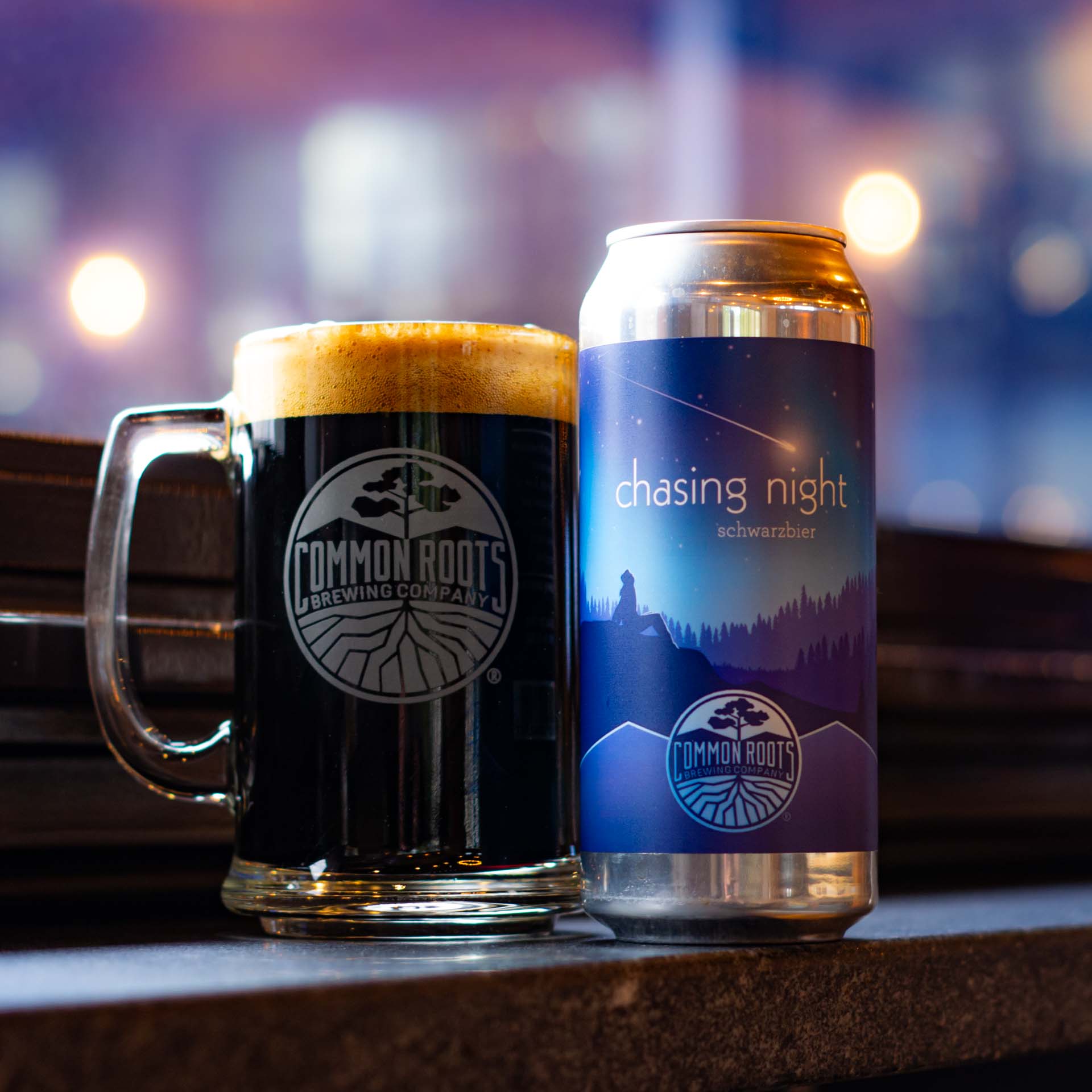 Can of Chasing Night next to a mug of dark beer