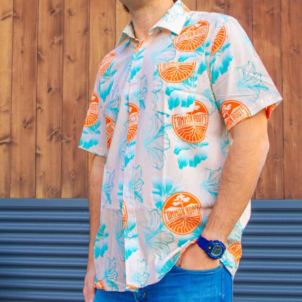 Pale orange button-down short sleeved hawaiian shirt with teal hibiscus flower pattern