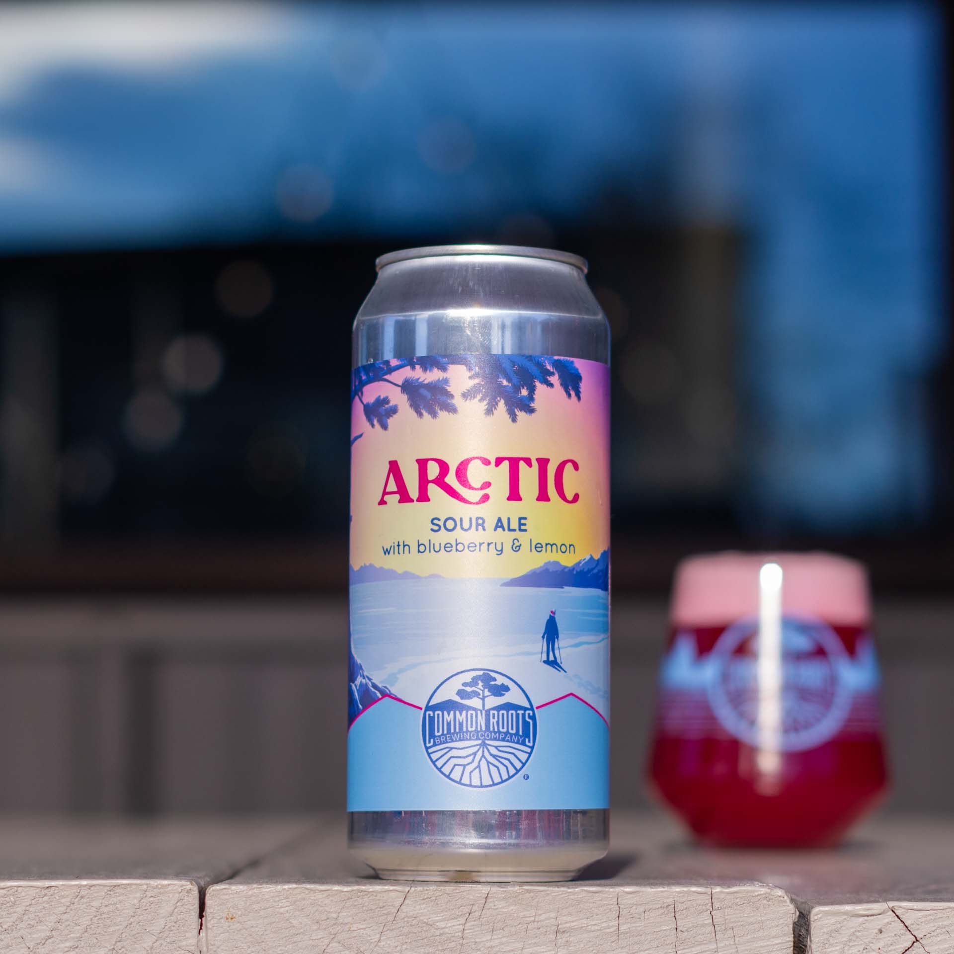 Can of Arctic next to a glass of colorful beer.