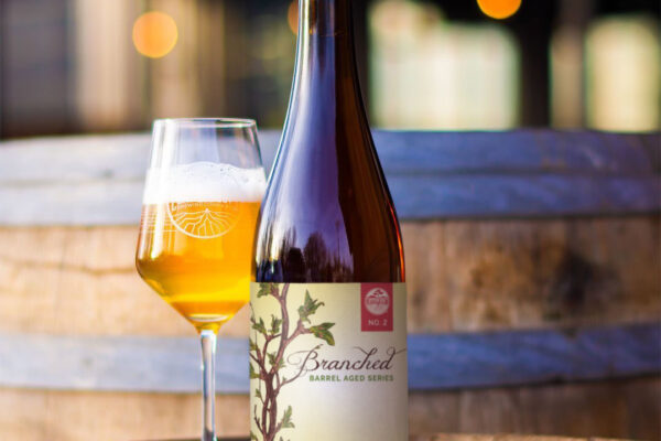 Bottle of Branched next to a stemmed glass of beer