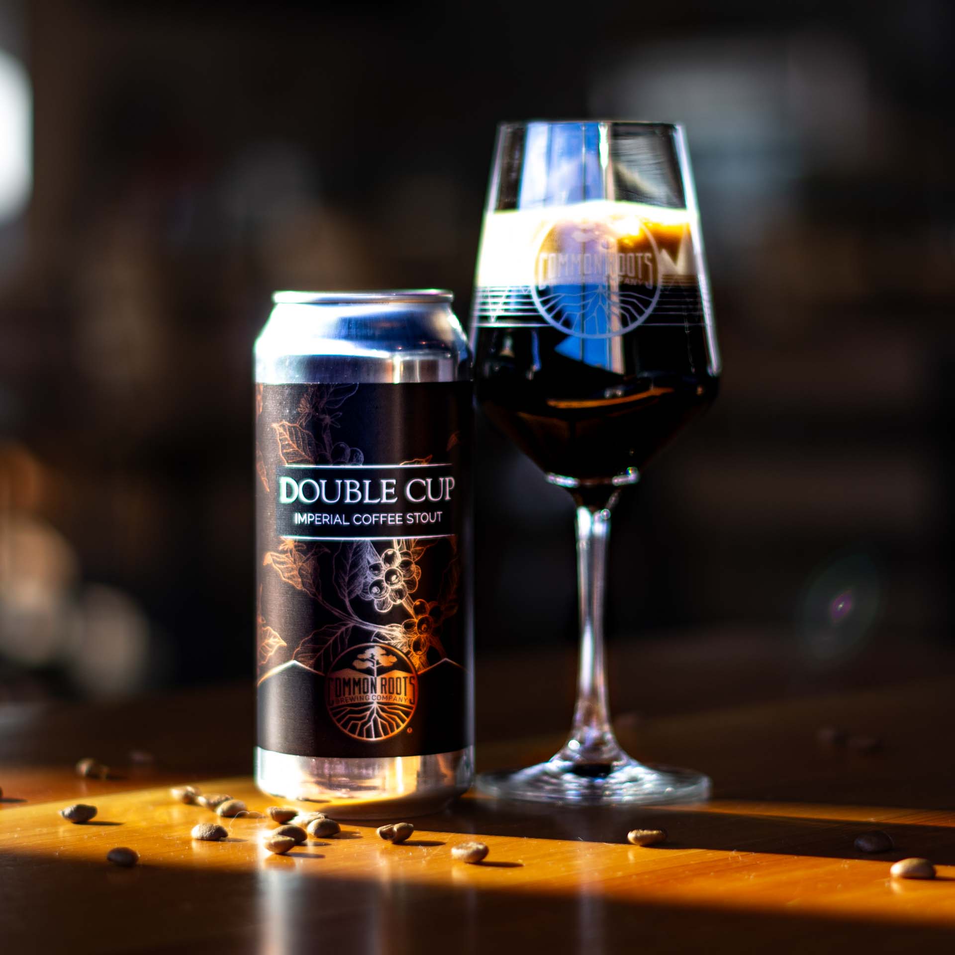 Can of Double Cup next to a stemmed glass of dark beer