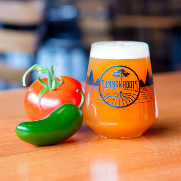 Glass of Michelada next to a pepper and a tomato.