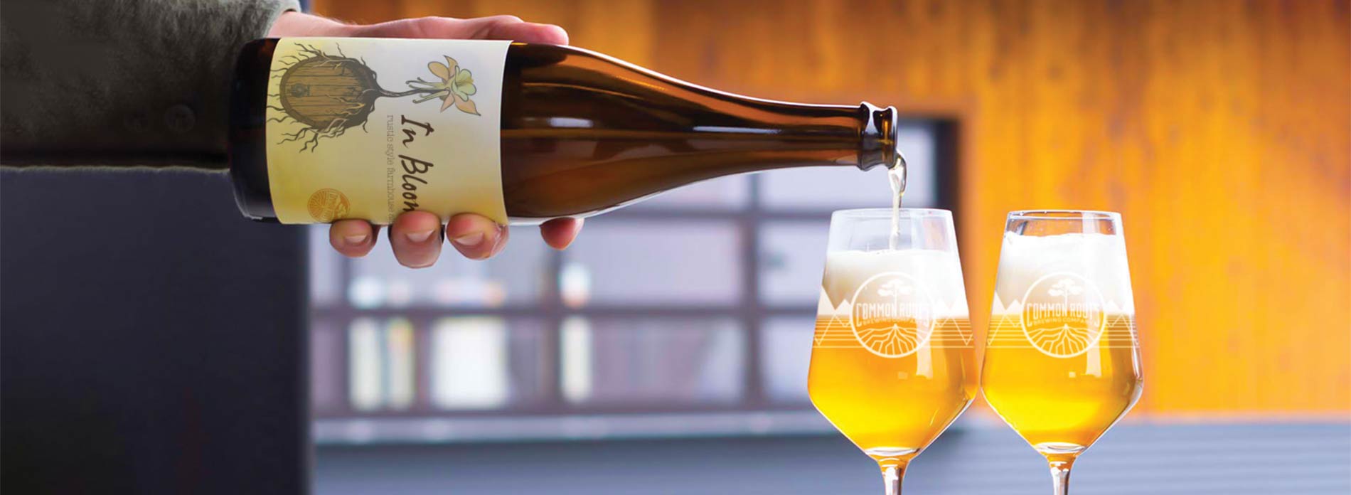 Bottle of Wild Beer being poured into two stemmed glasses