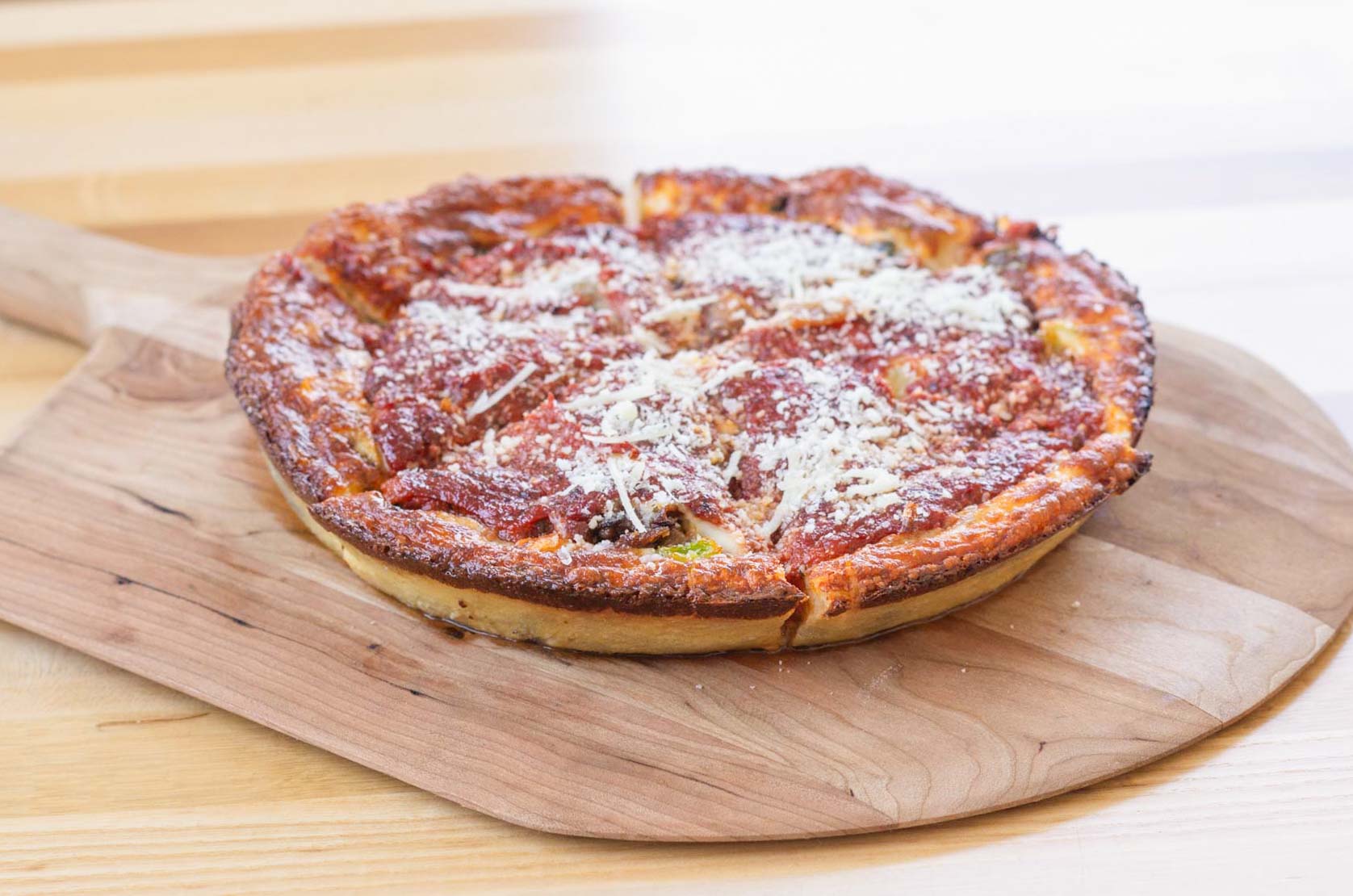 Thick crusted pizza on a wooden board with gooey cheese.