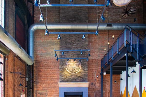 Large room with massive stone fireplace, brick walls, and long wooden tables