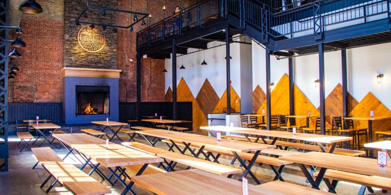 Large room with massive stone fireplace, brick walls, and long wooden tables