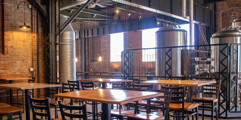 Balcony seating with high top tables and brewing equipment nearby