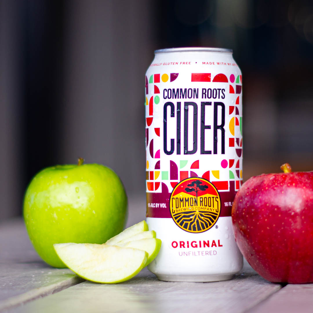Can of Common Roots Cider with apples next to it