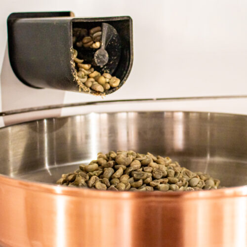 Green coffee pouring into hopper