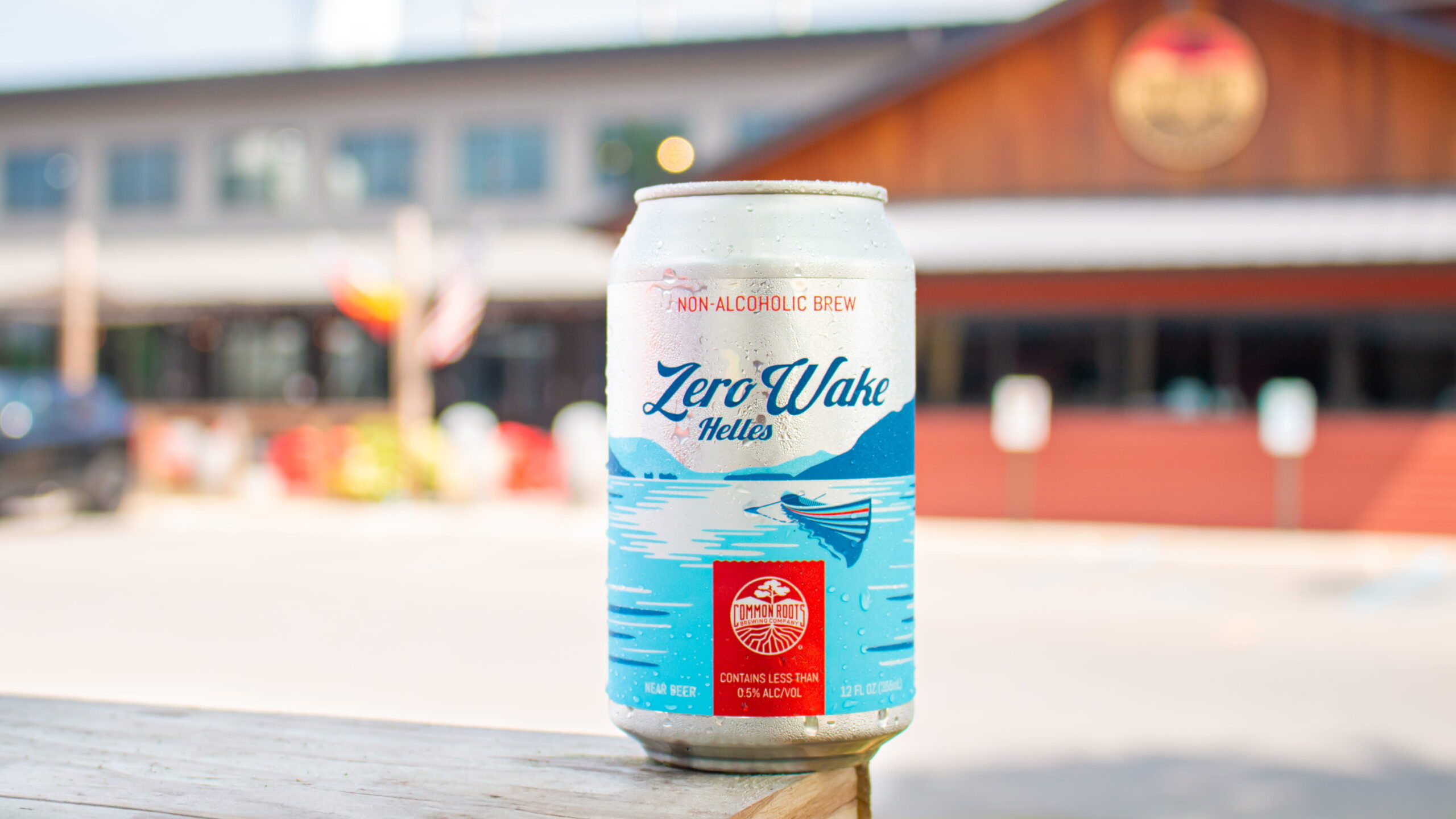 Can of Zero Wake NA Helles with Brewery in background