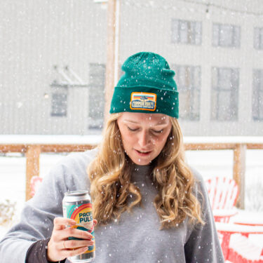 Woman wearing retro beanie holding Pacific Pulse