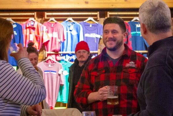 Christian Weber smiling with customers while holding a beer.