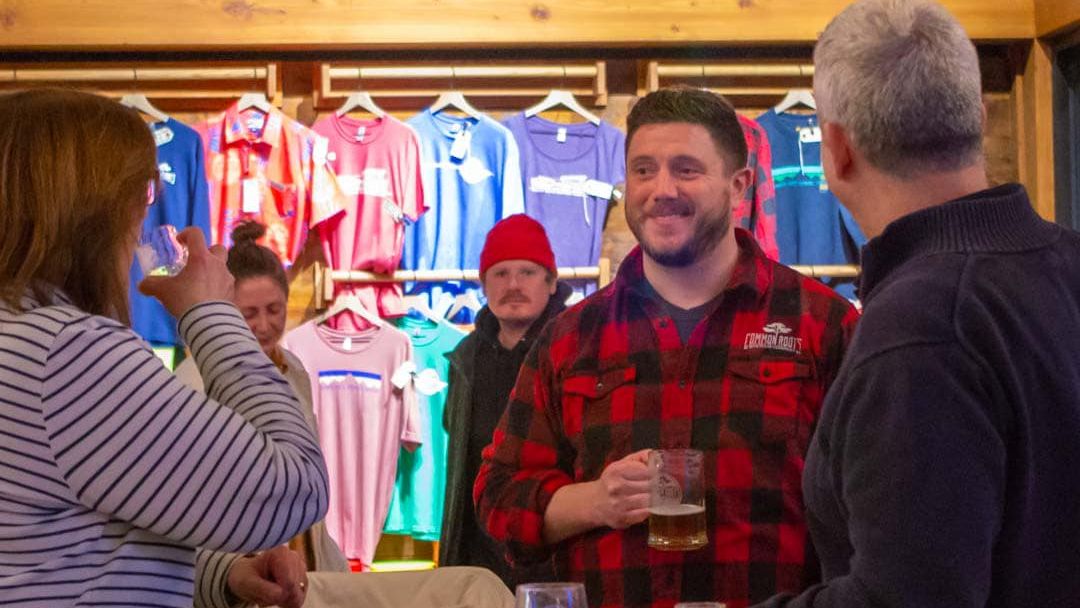 Christian Weber smiling with customers while holding a beer.