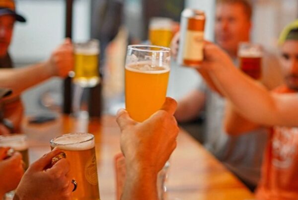 Several people raising a Common Roots glass around a table.