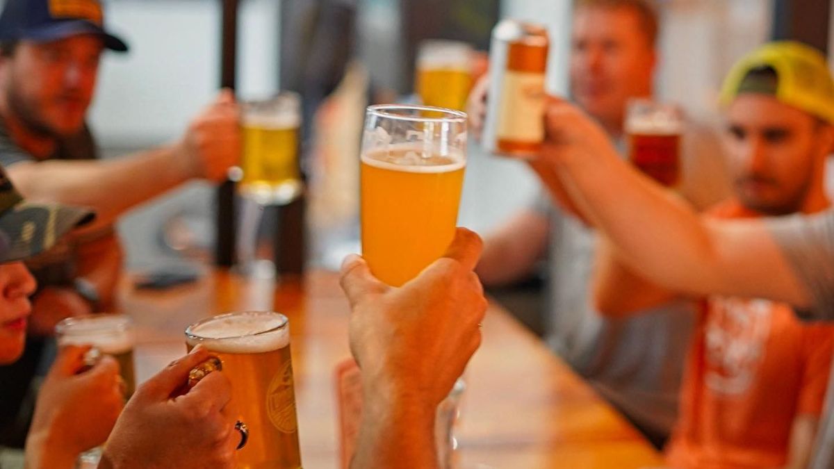 Several people raising a Common Roots glass around a table.